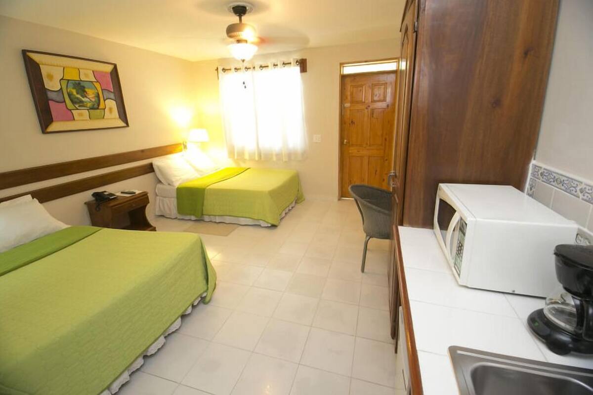 A hotel room with two beds, a desk, a microwave, and a sink.