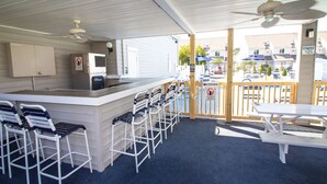 A covered outdoor area with a bar, seating, and a poolside view. - Deercreek Townhomes (Surfside Beach)