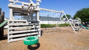 A playground with a swing set, tire swing, and climbing structure. - Deercreek Townhomes (Surfside Beach)