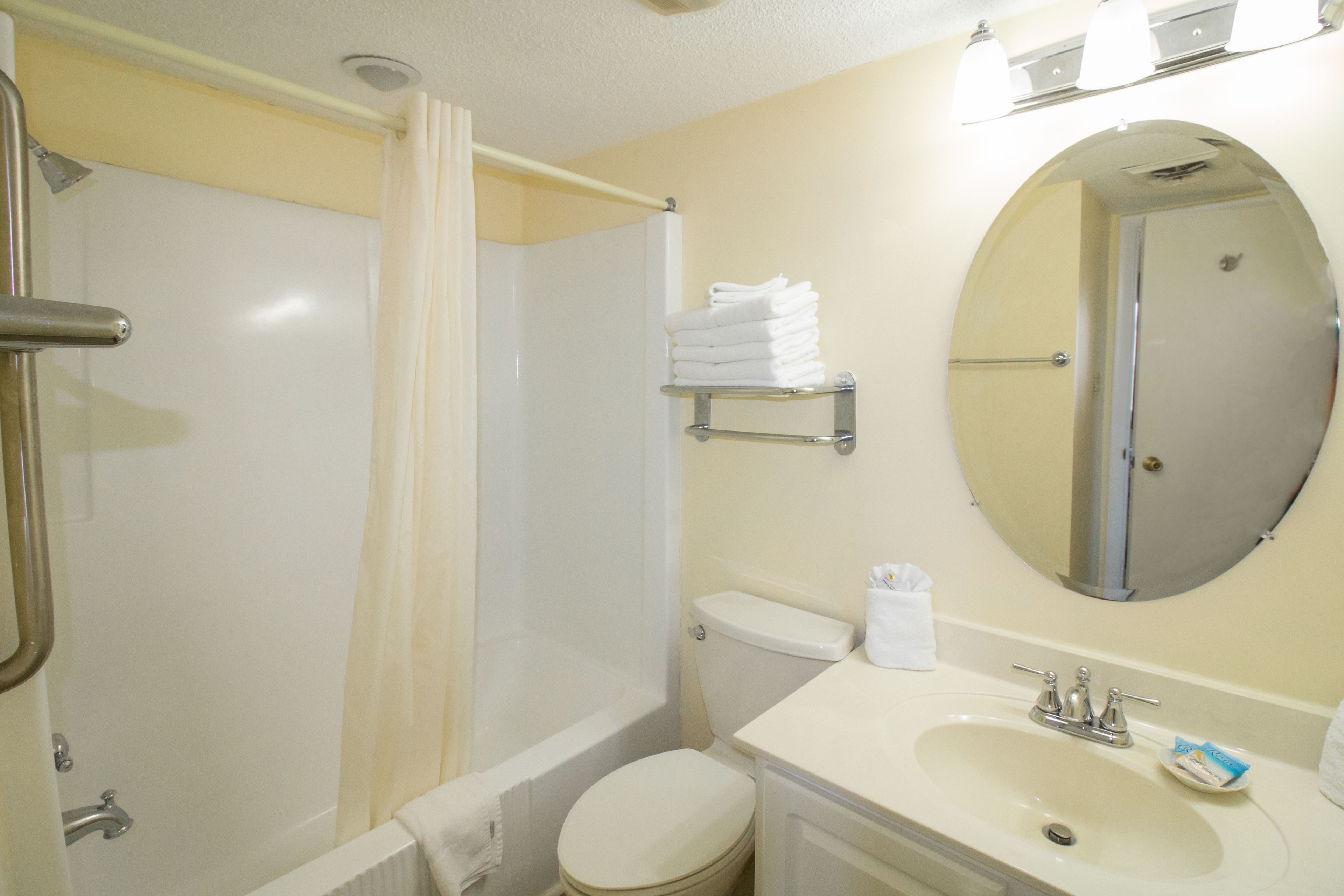 A bathroom with a bathtub, toilet, sink, and a mirror.