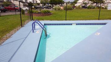 Enjoy a refreshing swim in the pool surrounded by lush greenery and a brick border.