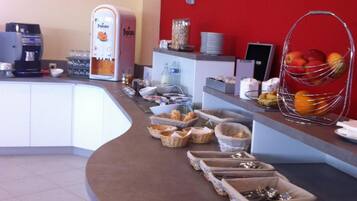 A breakfast bar with a coffee machine, fruit, and various food items.