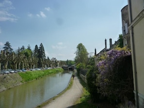 A canal with a pathway alongside, lined with trees and buildings. - Brit Hotel Montargis (Mormant-sur-Vernisson)