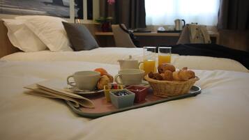 Una bandeja de desayuno bien presentada sobre la cama, con croissants, jugo de naranja y tazas de café.