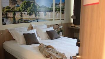A hotel room with a large bed, a view of Notre Dame Cathedral, and a sign indicating the room is in Paris.