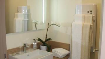 Un baño moderno con un lavabo grande, espejo y perchero para toallas.