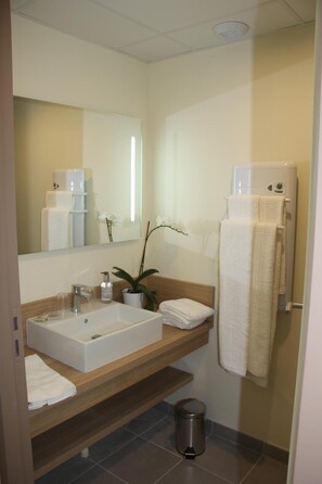 A modern bathroom with a large sink, mirror, and towel rack. - Brit Hotel Montargis (Mormant-sur-Vernisson)