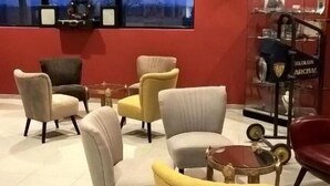 Un interior moderno con varias zonas de estar, un ventanal con vistas a árboles y una pared roja con un letrero que indica el número de habitación N7.