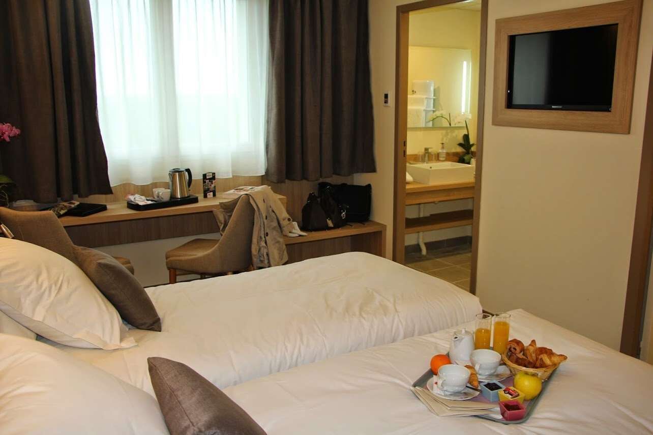 Una habitación de hotel con cama, escritorio, silla y bandeja de desayuno.