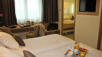 Una habitación de hotel con cama, escritorio, silla y bandeja de desayuno.
