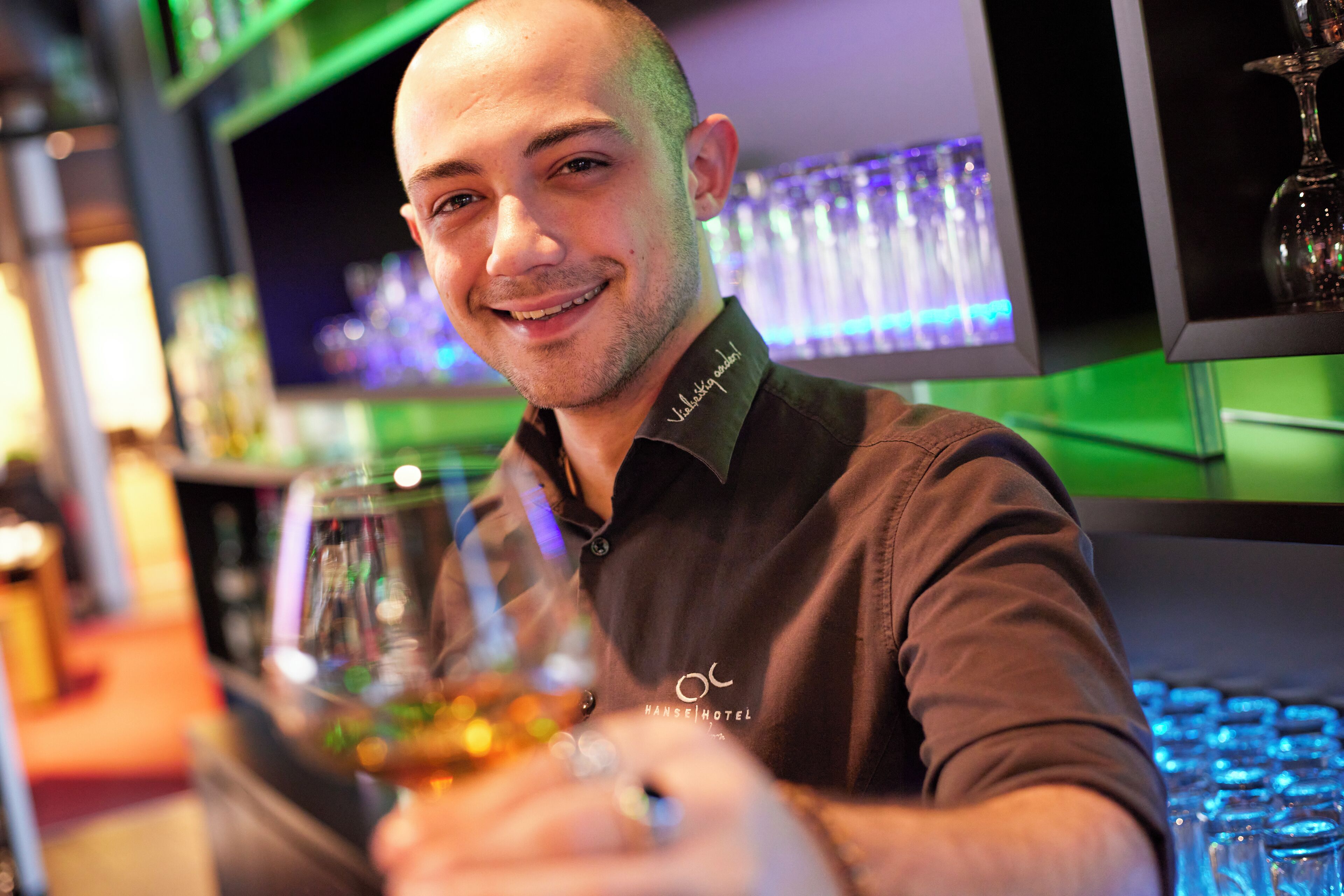 A bar setting with a bartender holding a glass.