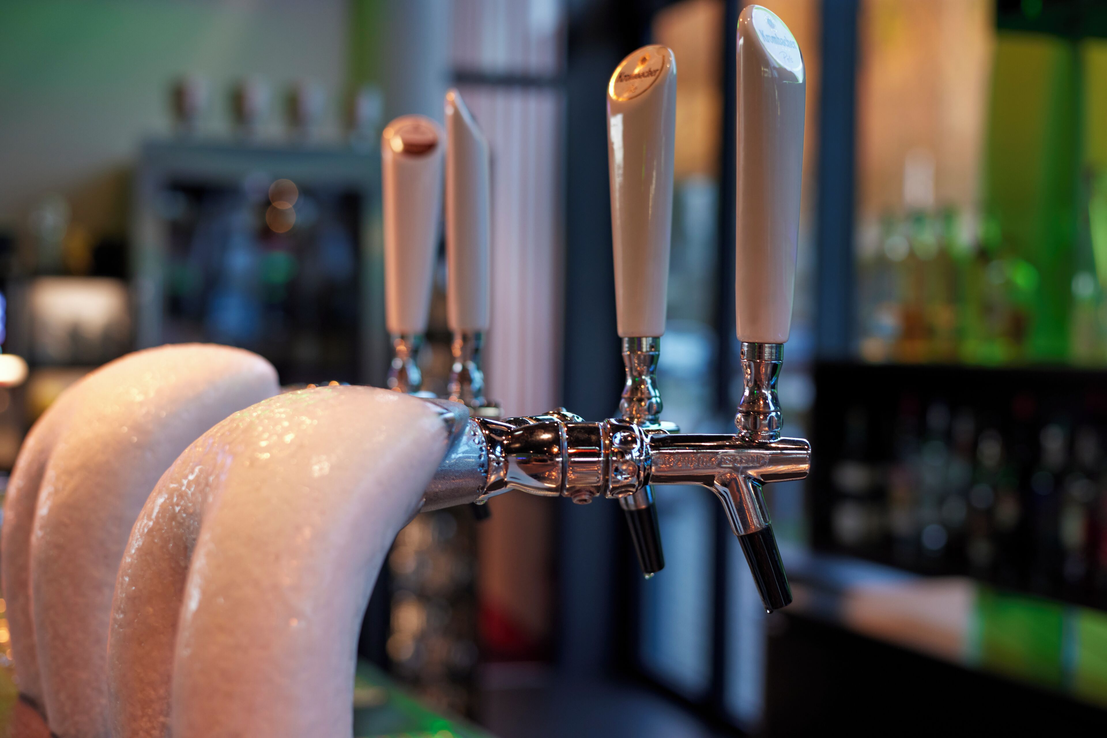 Un bar con múltiples grifos y botellas al fondo.
