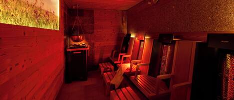 Un cuarto de sauna con bancos de madera y un calentador de sauna fijado a la pared.