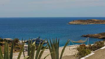 A coastal view with a hammock, a boat, and a rocky island.