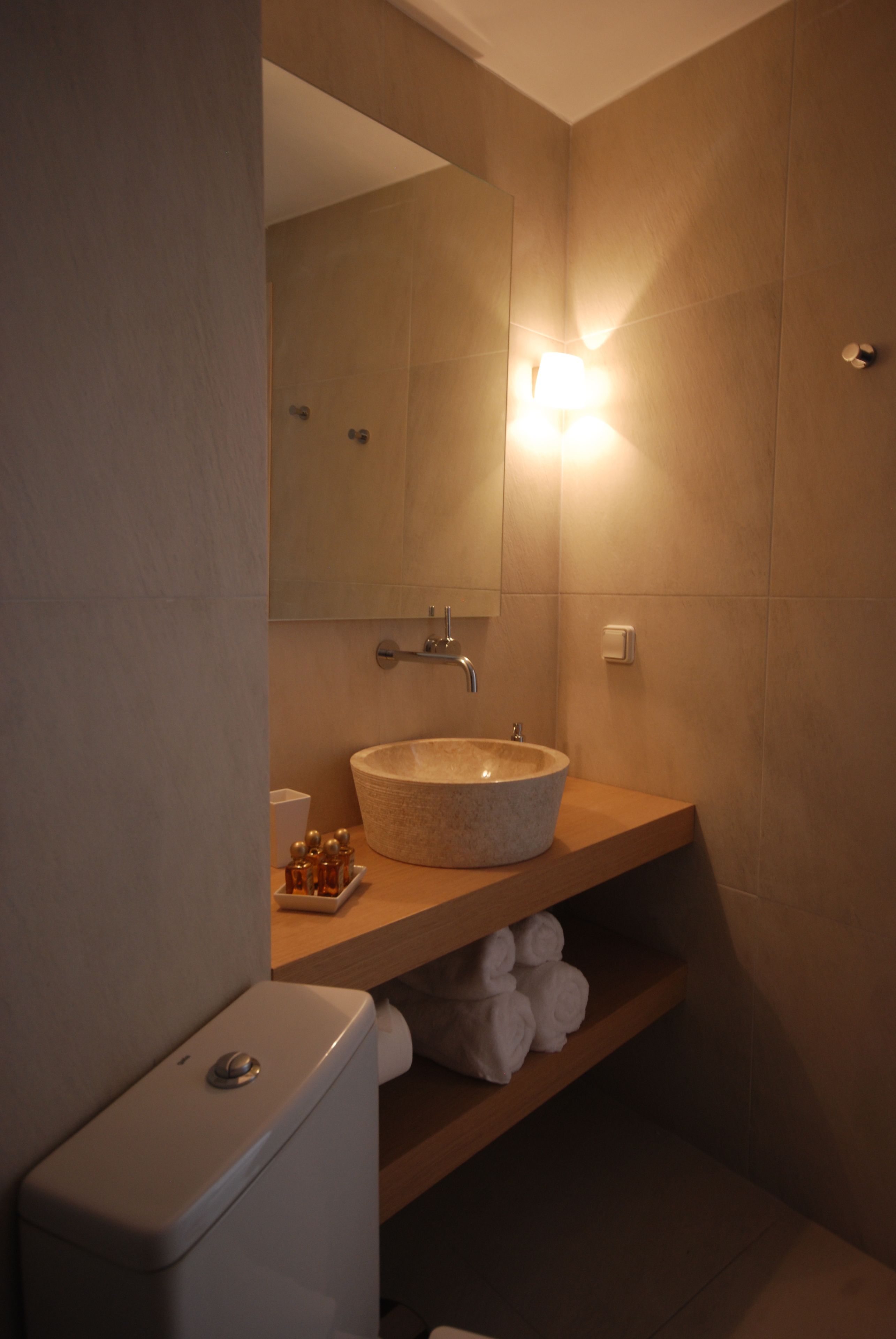 A bathroom with a round sink, a mirror, a towel rack, and a toilet.