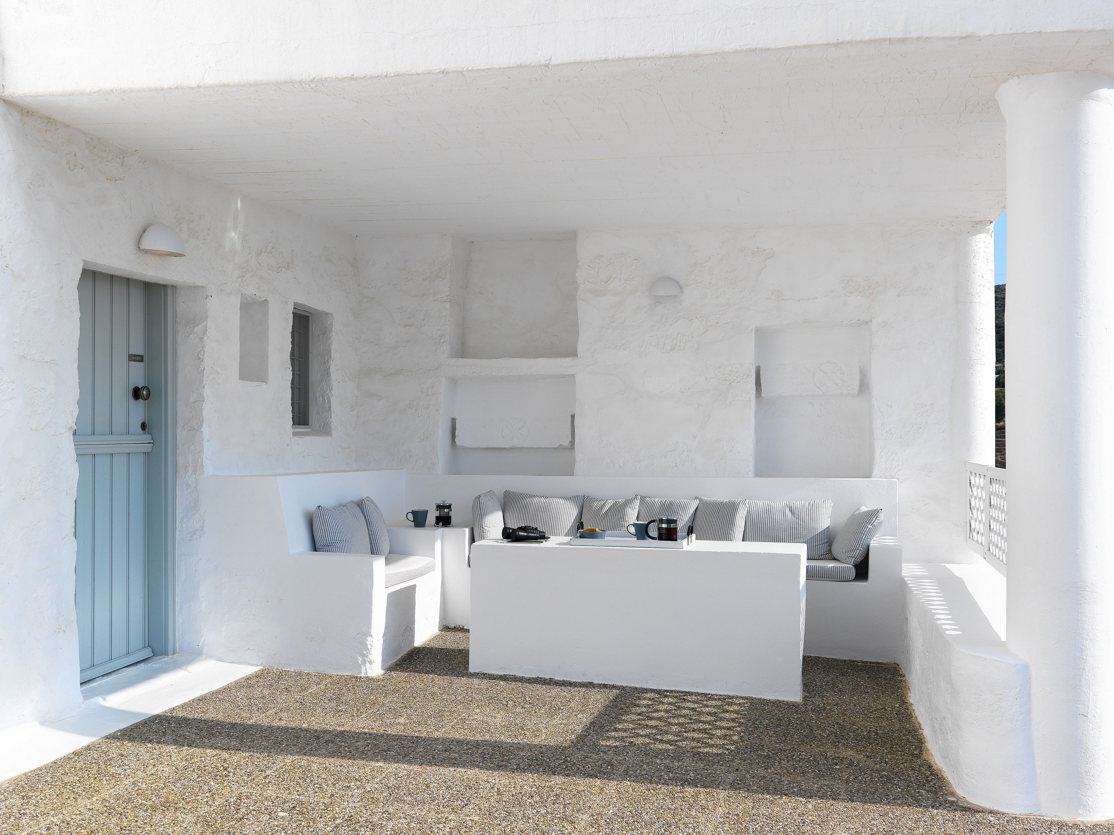 A white interior with a blue door, a seating area with cushions, and a coffee table.