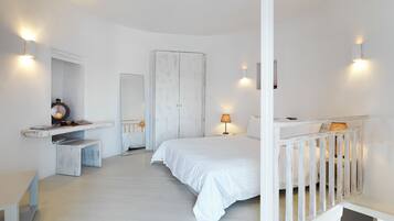 A bedroom with a bed, a nightstand, a mirror, a wardrobe, and a small desk with a lamp.