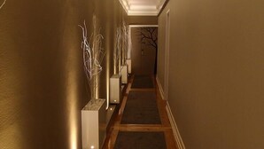 A narrow hallway with a wooden floor and white planters with branches. - Castilho House (Lisbon)