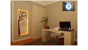 A hotel room with a desk, a chair, a plant, and a 'Clean & Safe' sign on the wall. - Castilho House (Lisbon)