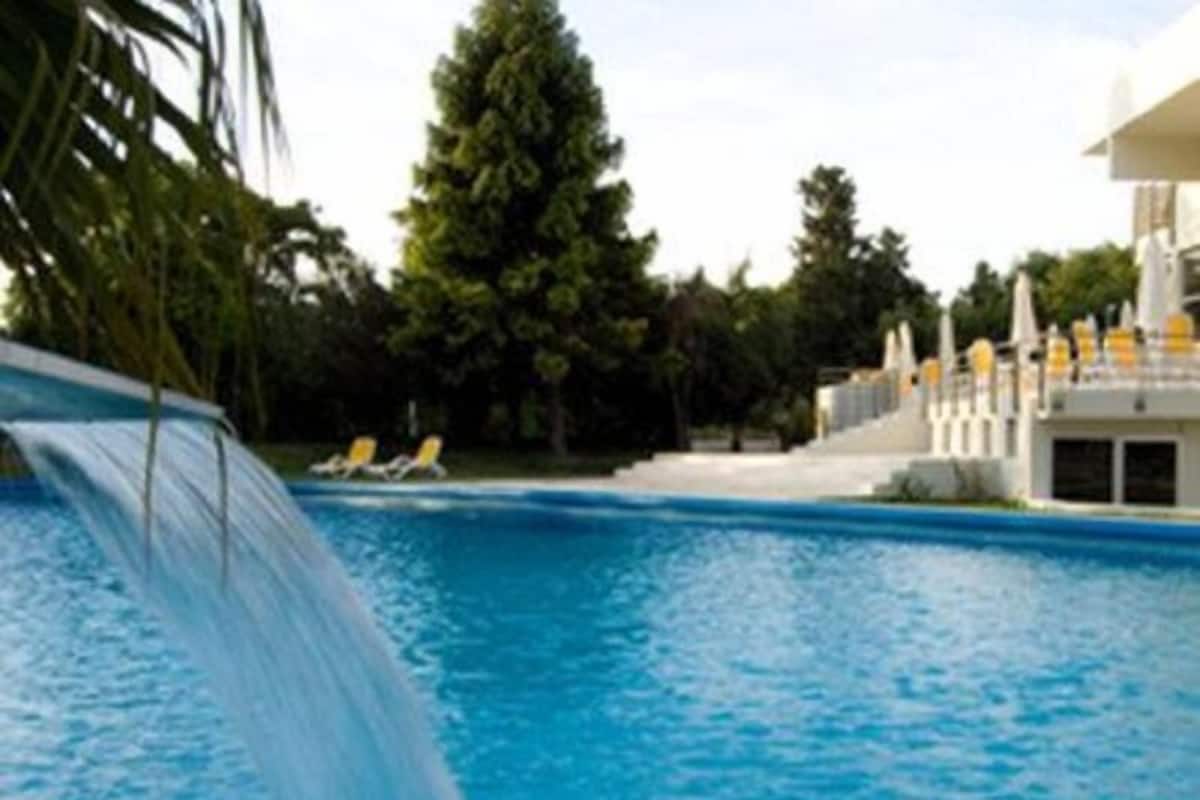 A swimming pool with a water slide, lounge chairs, and a building with a white facade.