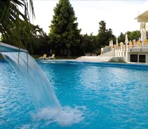A swimming pool with a water slide, lounge chairs, and a building with a white facade. - Howard Johnson by Wyndham Plaza Hotel Mayorazgo (Parana)