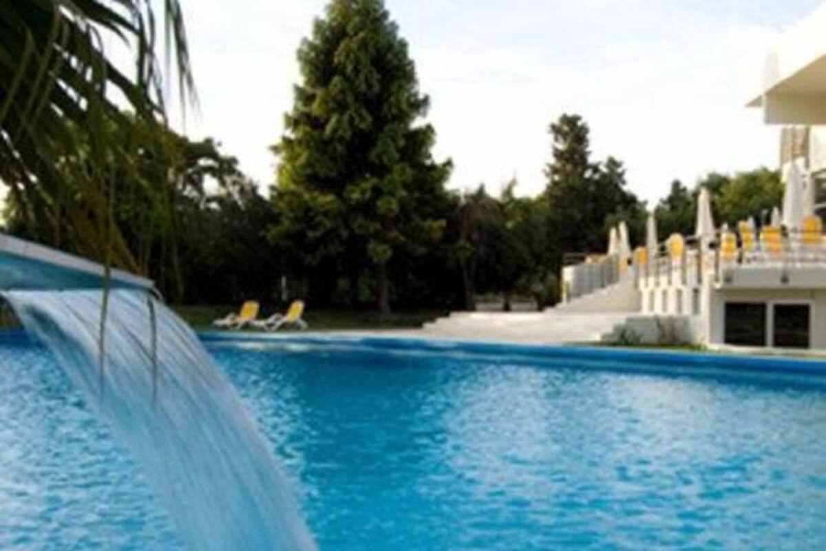 A swimming pool with a water slide, lounge chairs, and a building with a white facade.