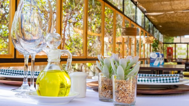 A table with a clear glass decanter, a pitcher, and two small glass containers with plants. - Geotel Calama (Calama)