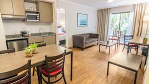A modern kitchen with a microwave, sink, and cabinets. There is a dining area with a table and chairs, and a sofa in the living room. - Geotel Calama (Calama)
