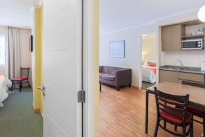 A hotel room with a dining area, kitchenette, and a sofa.
