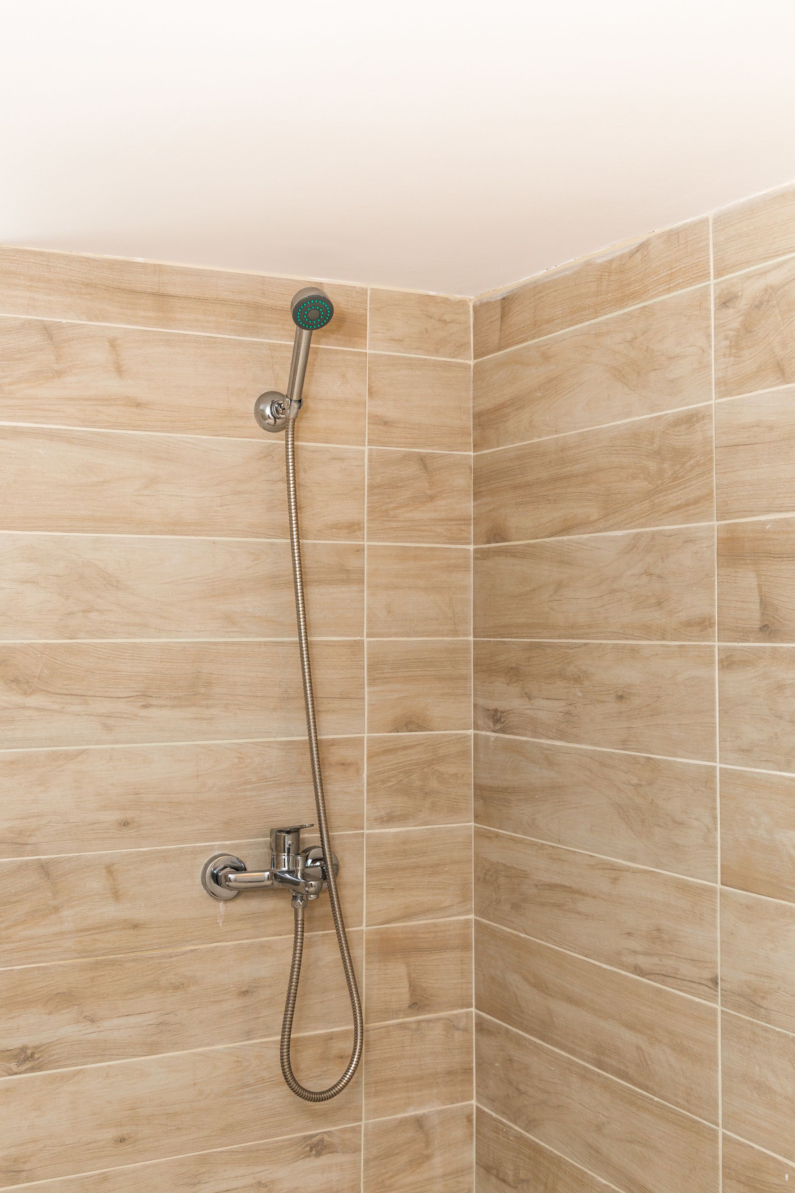 A shower with a handheld hose and a wall-mounted control.