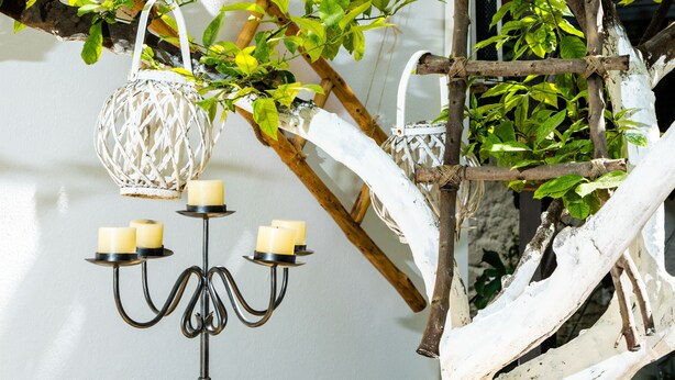 A wooden table with a white decorative stand and a hanging white lantern.