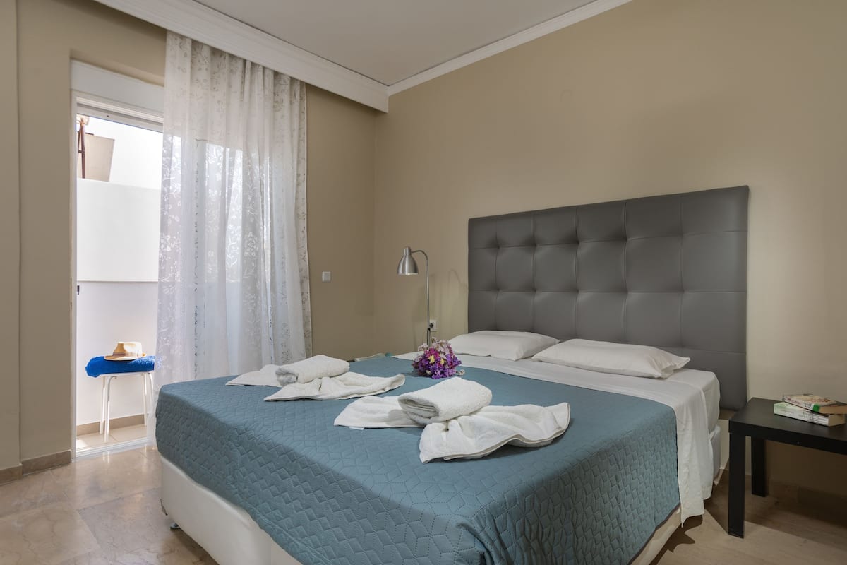 Ein Hotelzimmer mit einem großen Bett, einem Nachttisch und einem Fenster mit Vorhängen.
