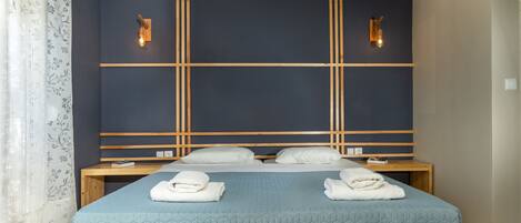 Een hotelkamer met een groot bed, twee nachtkastjes, een houten hoofdeinde en wandlampen.