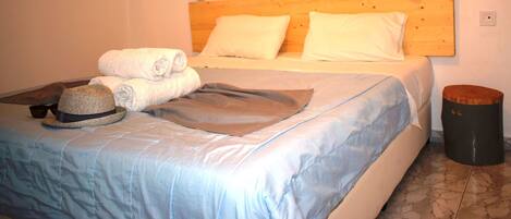 A neatly made bed with a wooden headboard, two bedside lamps, and a round wall clock.