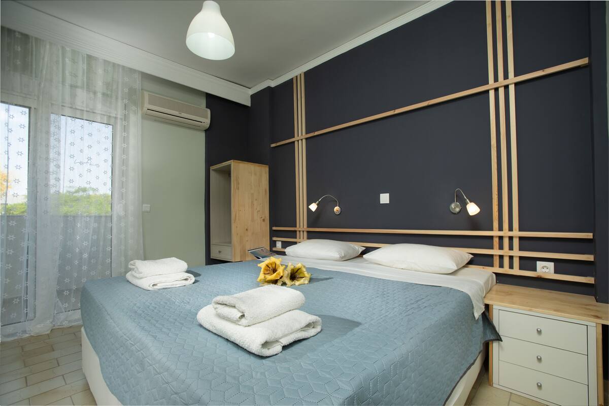 Ein Schlafzimmer mit Bett, Nachttischen, einem Kleiderschrank und einem Fenster mit Vorhängen.
