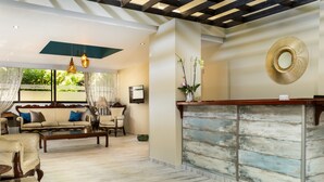 A spacious lobby with a wooden reception desk, comfortable seating, and a large mirror on the wall.