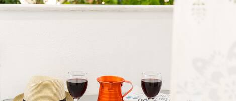 A table with a straw hat, two wine glasses, and an orange pitcher.