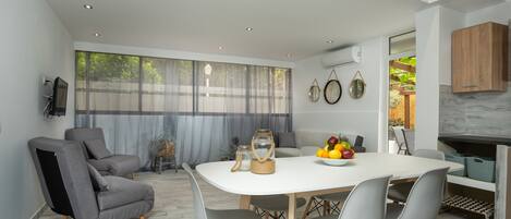 Un comedor moderno con una mesa blanca, sillas grises y un frutero.