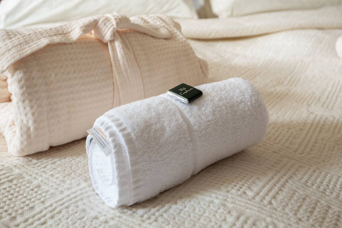 A neatly made bed with white linens and a wooden headboard.