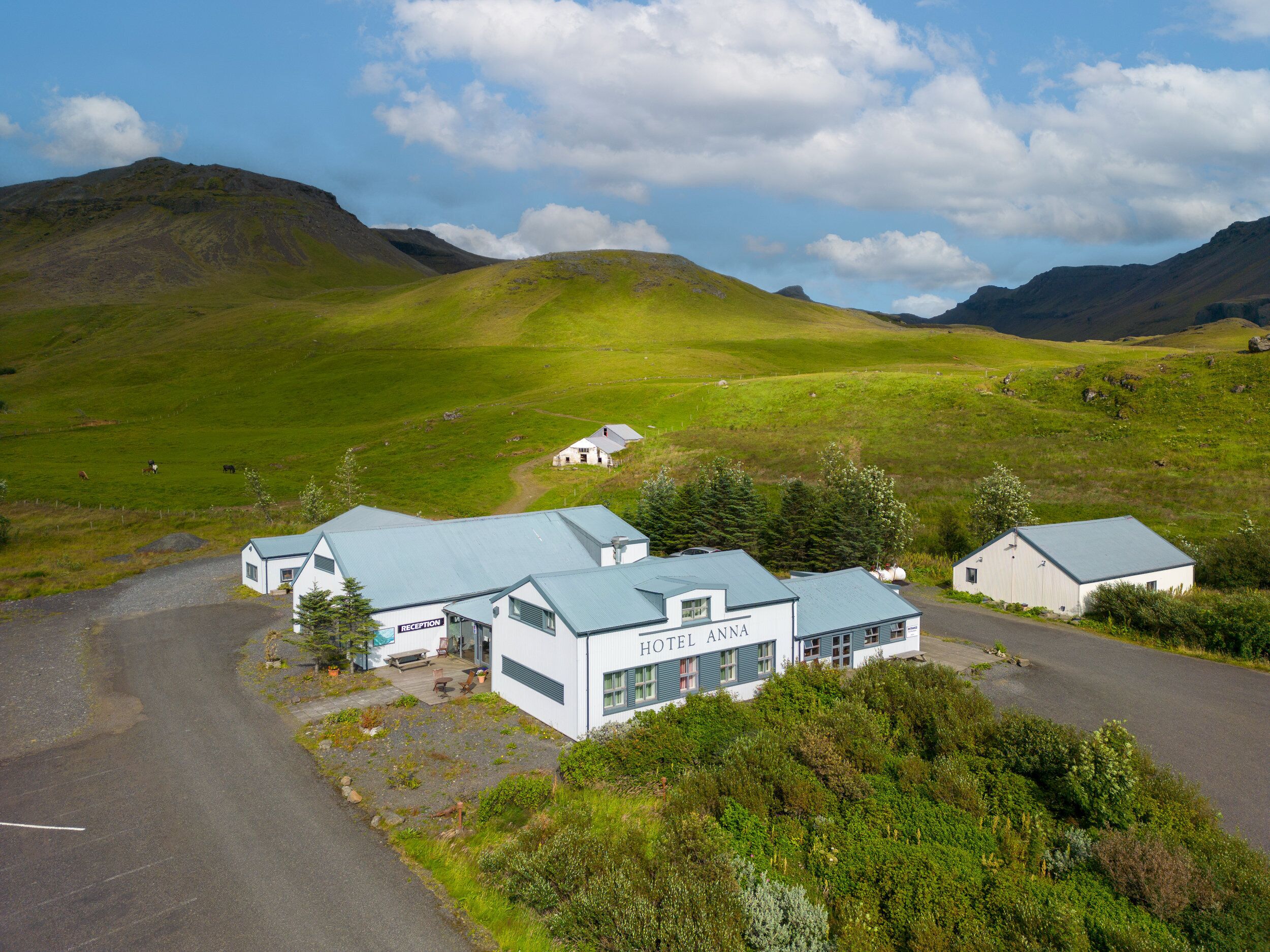 A hotel with a reception area, multiple rooms, and a view of rolling hills and mountains.