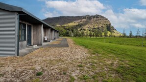 A building with a metal exterior and a paved walkway leading to a grassy area.