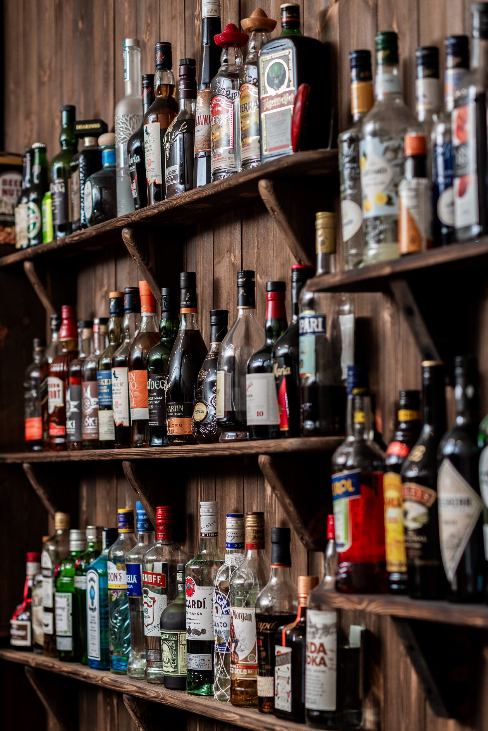 A wooden shelf with various liquor bottles.