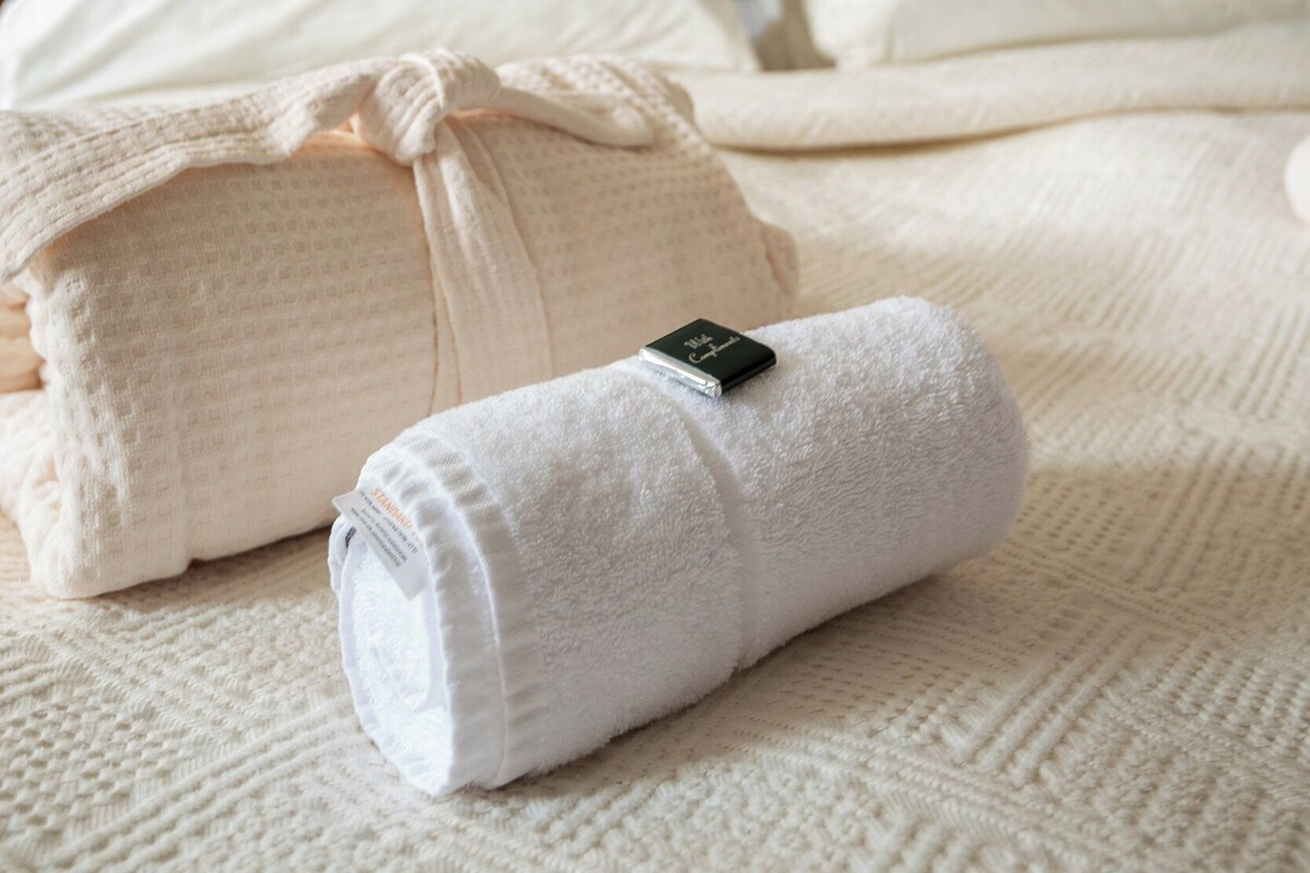 A neatly made bed with white linens and a wooden headboard.