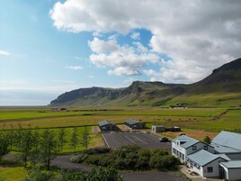 Un hotel con estacionamiento, rodeado de campos verdes y montañas.