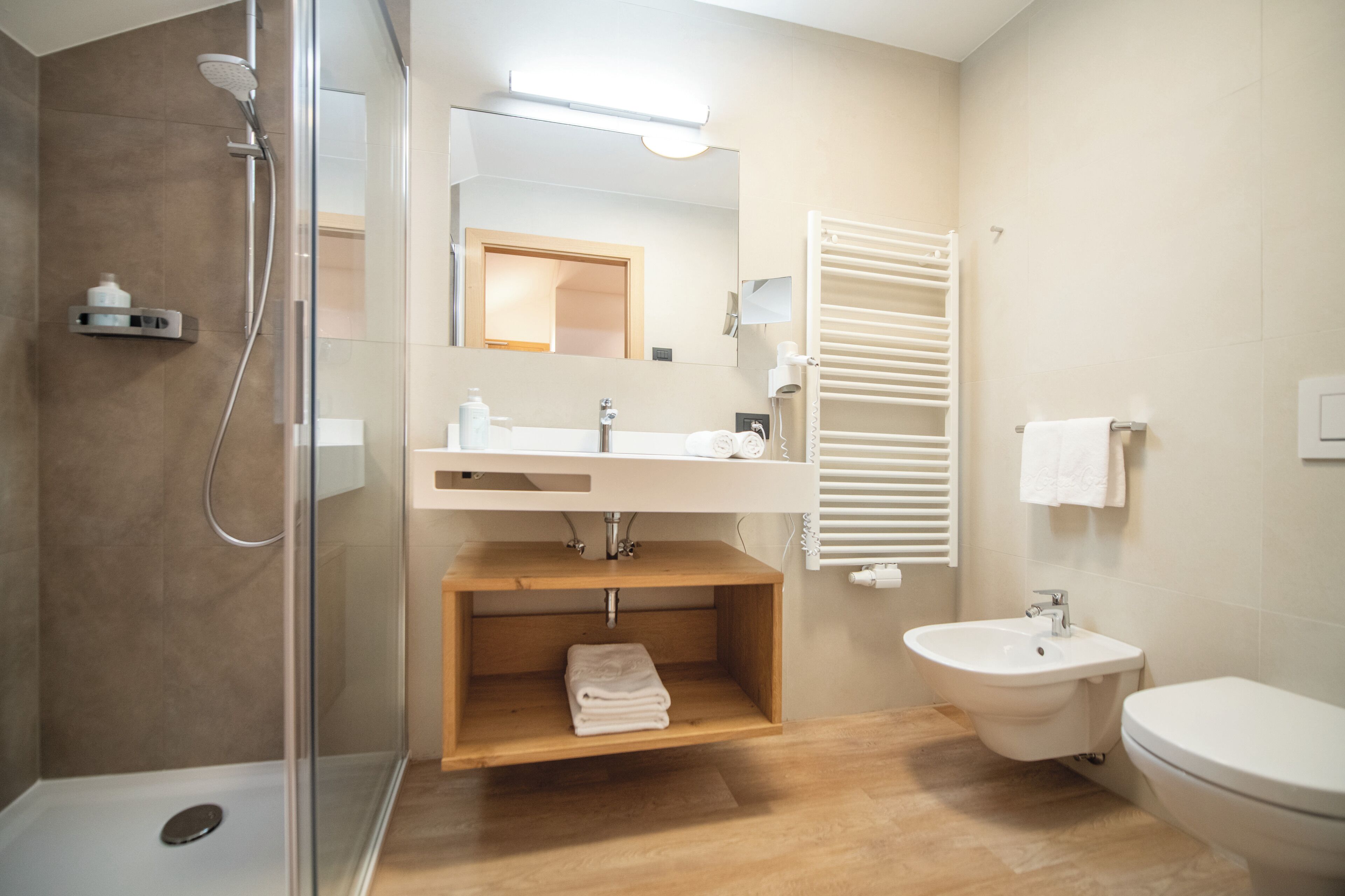 A modern bathroom with a glass-enclosed shower, a wooden vanity, a sink, and a toilet.