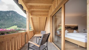 Un balcón de madera con una cama, una silla y una mesa.