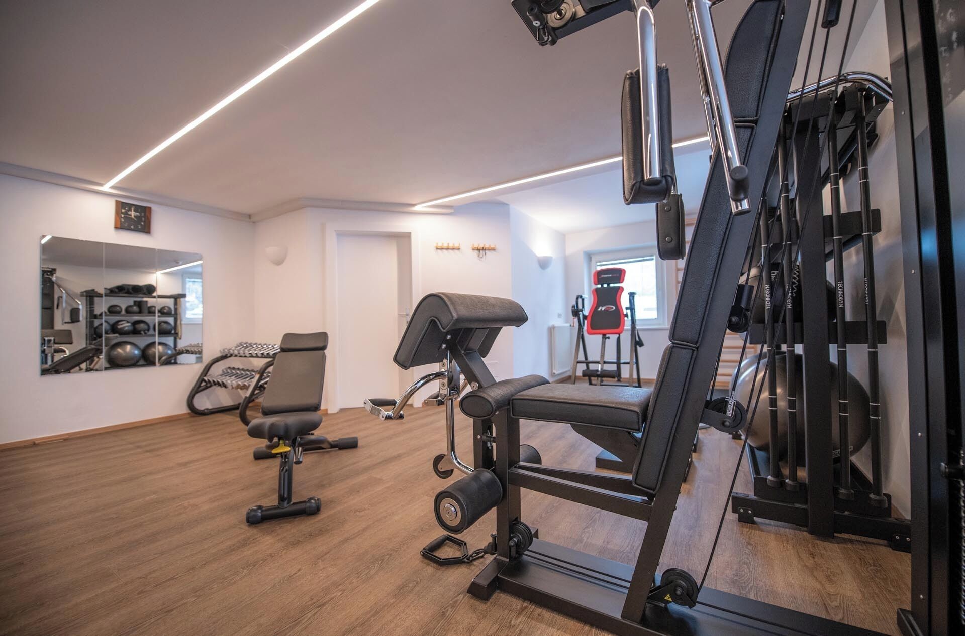Un gimnasio con equipamiento de ejercicio, un espejo y un soporte para pesas.