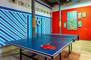 A ping pong table with two paddles and a ball, a wall with geometric patterns, and a red wall with abstract art. - Pop Art Hotel CLC Mamonal Cartagena (Cartagena)