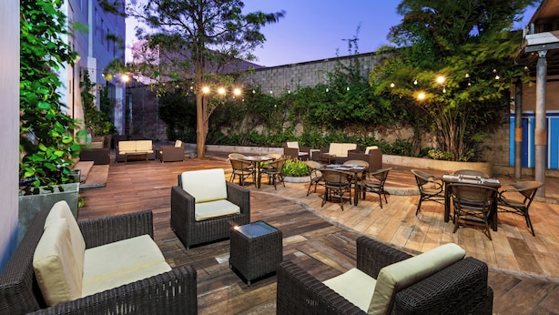 An outdoor patio area with wicker furniture, a stone wall, and string lights. - Pop Art Hotel CLC Mamonal Cartagena (Cartagena)