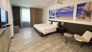 A hotel room with a bed, a TV, a ceiling fan, a small table, and a chair. - Pop Art Hotel CLC Mamonal Cartagena (Cartagena)